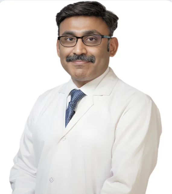 Portrait of a male doctor wearing a white coat, blue tie, and glasses, looking at the camera.